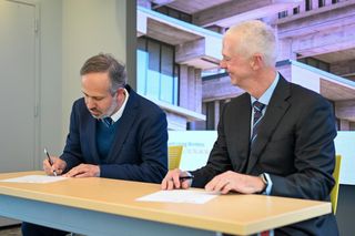 Two officials sign document at table