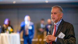 Charlton College of Business Dean Madan Annavarjula addresses a room of alumni, business leaders, and legislators in Boston
