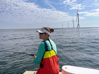 Dr. Lauran Brewster on a boat with wind turbines in the background