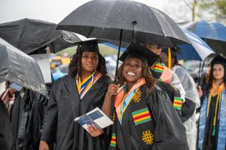 Two students in graduation regalia smiling