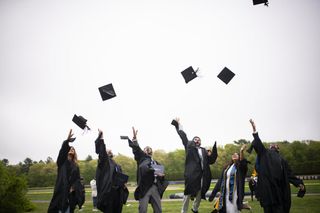 students throwing graduation caps in air