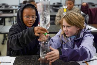 Two children in the STEM4Girls program do an experiment with water bottles
