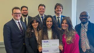 A group of UMass Law students pose with a shared reason they walk—for our community.