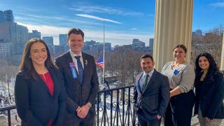 Walk the Hill captains pose on the Massachusetts State House balcony.