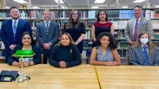 Students sitting and standing at desk in law library