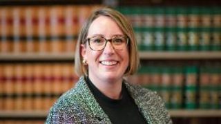 Female student standing in front of law books