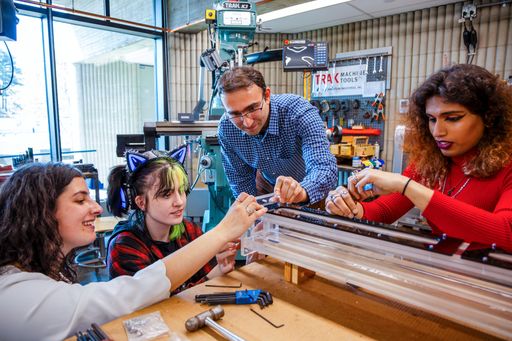 Professor assisting students with mechanical engineering capstone project