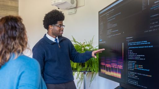 Data science major talking with faculty about a data visualization on screen