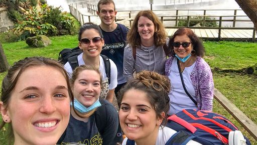 Students and faculty standing in front of a waterfall