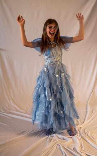 Look 6, 2026, blue ballet-length dress with cascading ruffles in chiffon and tulle, paired with a blue vinyl capelet, all finished with silver faux-leather accents.