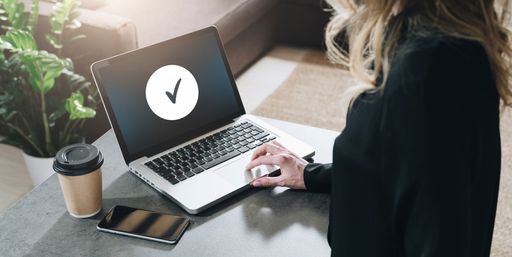 Rear view. Young woman, girl, student is sitting at table, working on laptop.