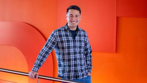 student logan cabral against red wall backdrop