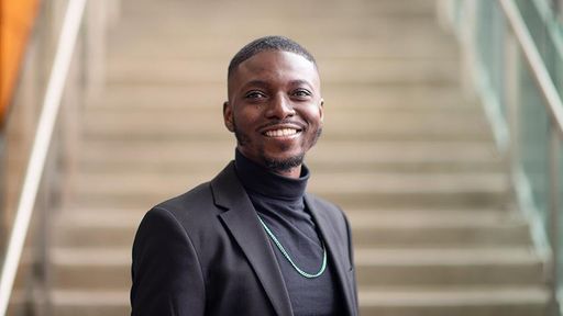 phd cybersecurity student gaspard baye in front of library staircase