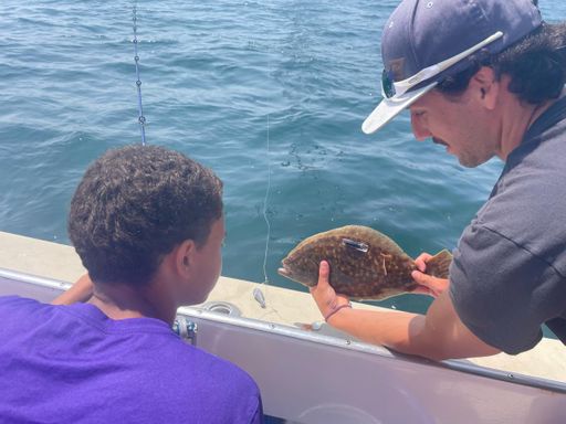 Cole Carrano shows NBHS student intern Eduardo Camilo a tagged fluke	