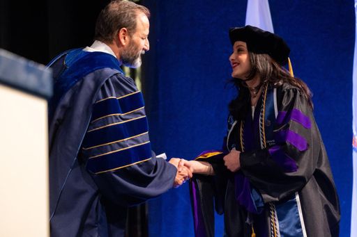 Aguilar Delgado pictured at commencement shaking the hand of UMass Law Dean Sam Panarella.