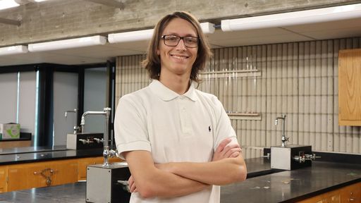 Elijah Facchiano standing with his arms crossed in front of lab benches