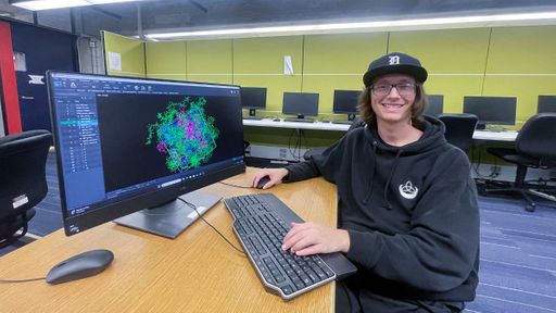 Elijah Facchiano sitting in front of a computer displaying his research
