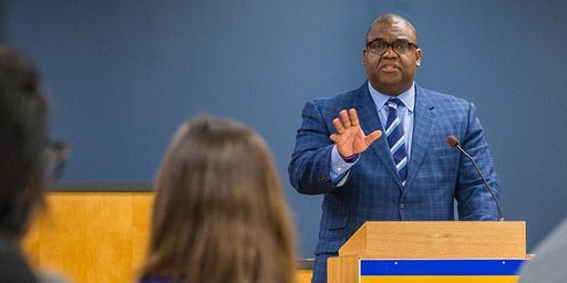 Judge stands at lectern with students in the foreground