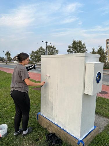 Illustration student Chloe Canterbury paints an electrical box alongside Route 18