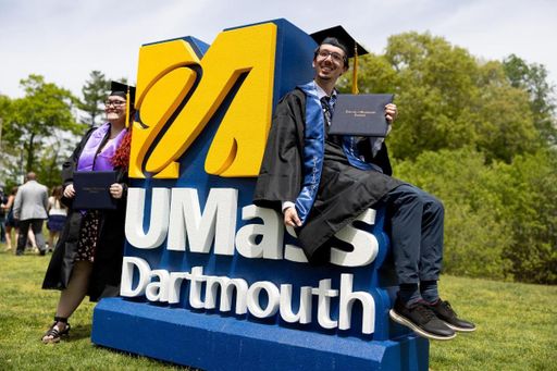 Students pictured on UMass Dartmouth's logo after Commencement.