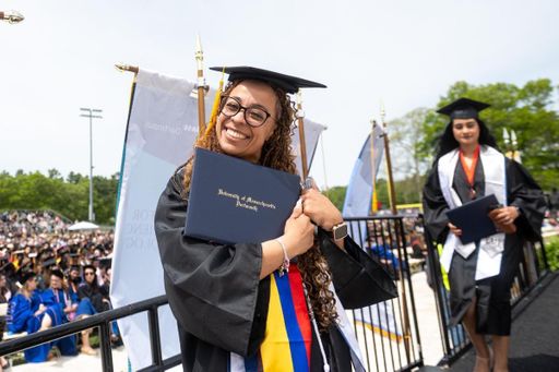 Student pictured with their diploma covers after crossing the stage at Commencement.