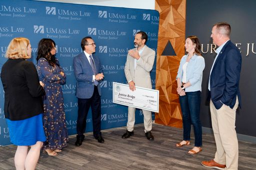 Bristol Wealth Group President and CEO Lou Ricciardi presents a $10,000 check to UMass Law Dean Sam Panarella.