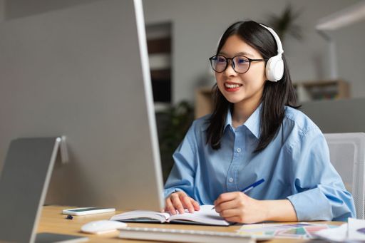 Student wearing headphones at her desk working on a computer