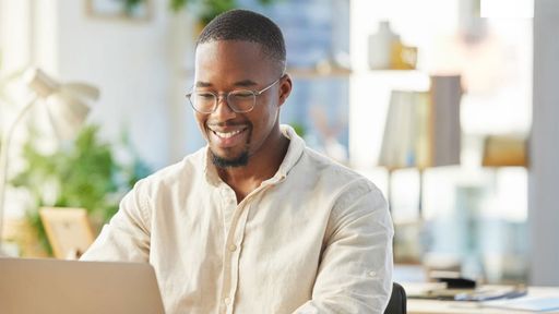 Young male student working on his laptop at his desk.