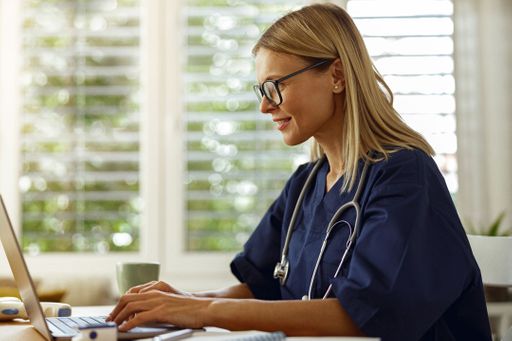 Healthcare professional sitting at the kitchen table working on her computer
