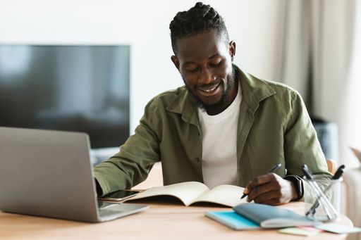 Man taking notes while on his laptop.
