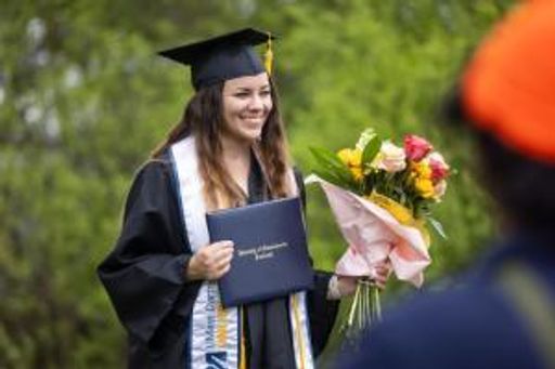UMassD Online Students posing on commencement stage with diploma