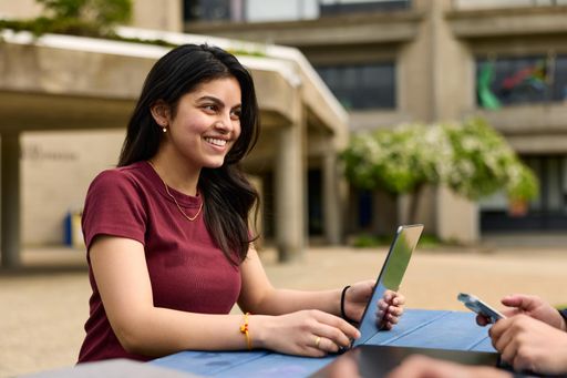 UMassD Student sitting outside on laptop