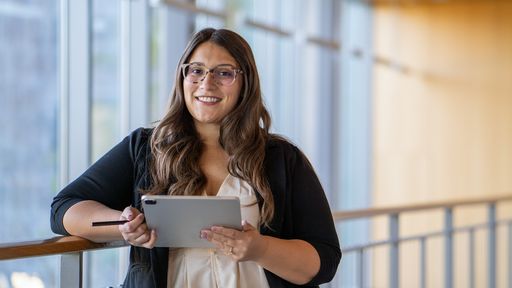 UMass Dartmouth student posing with ipad leaning against railing