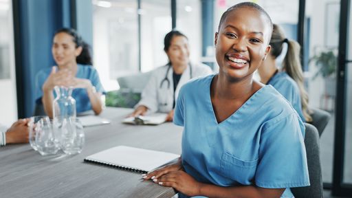 Nurse smiling and sitting in a meeting room