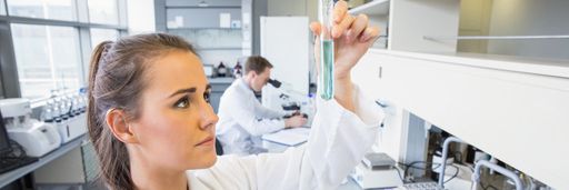 Young female scientist holding up test tube at the laboratory