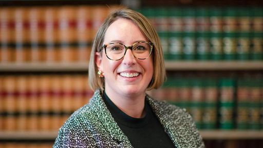 Female student standing in front of law books