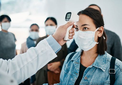 Young woman getting her temperature taken with an infrared thermometer by a doctor during an outbreak