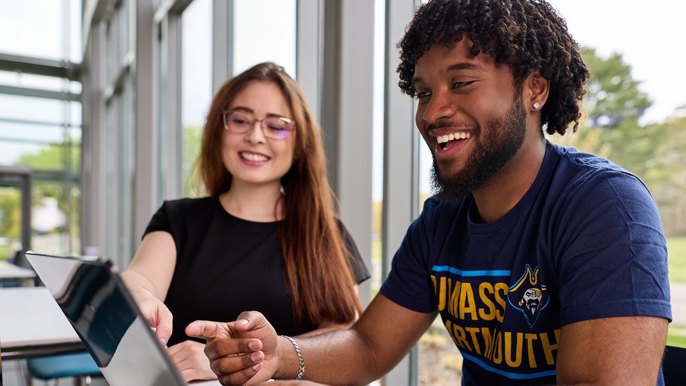 Two students studying in a glass atrium space