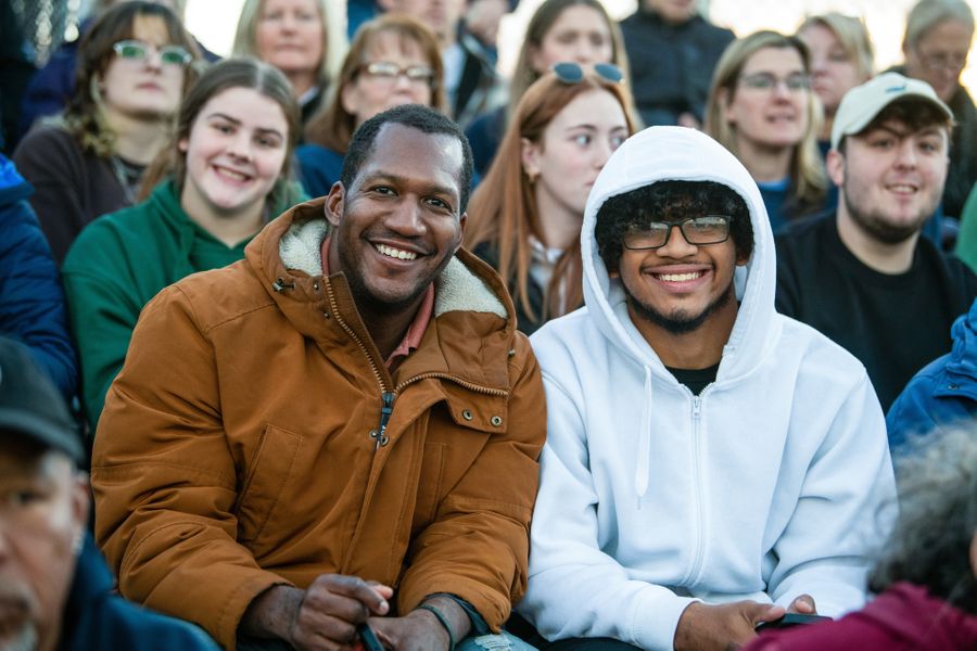 Smiling male students enjoying the football game on Blue and Gold Weekend.