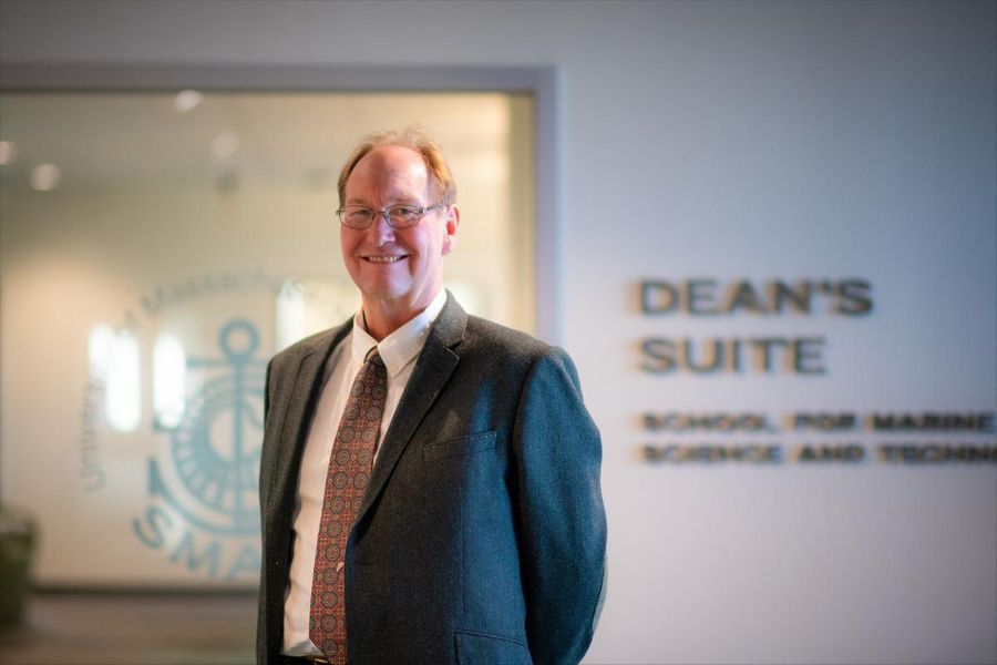 Kevin stokesbury posing in front of Deans office signage