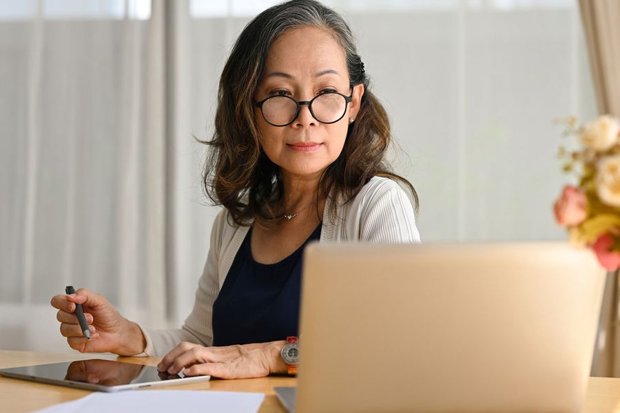 Woman working on laptop with tablet and stylus