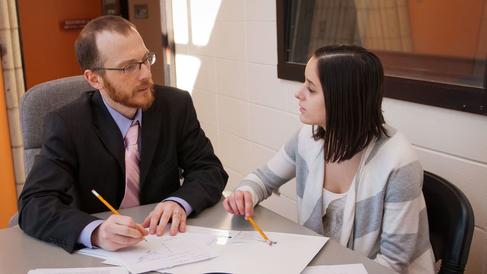 A psychology faculty and student sitting at a table together having a discussion