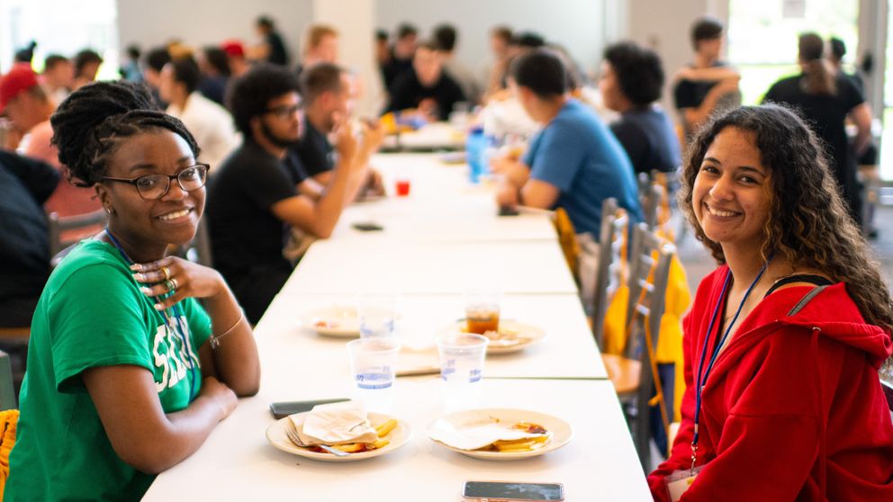 Students eating at the Grove at the end of a long table